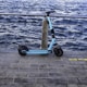 a blue scooter parked on a sidewalk next to a body of water