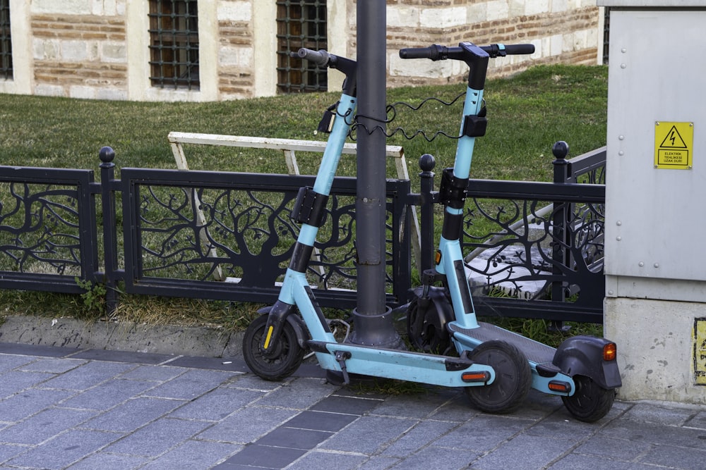 a blue scooter parked next to a black fence