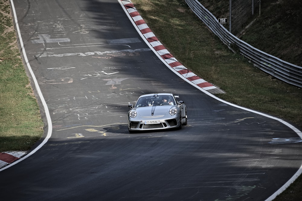 a silver sports car driving down a race track