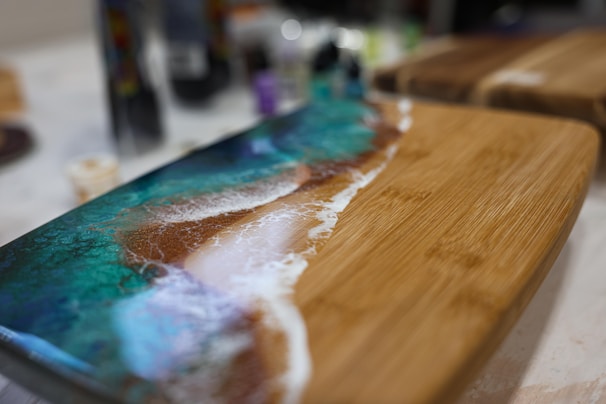 Close-up of a handcrafted epoxy serving board with ocean-inspired blue swirls and natural wood grain.