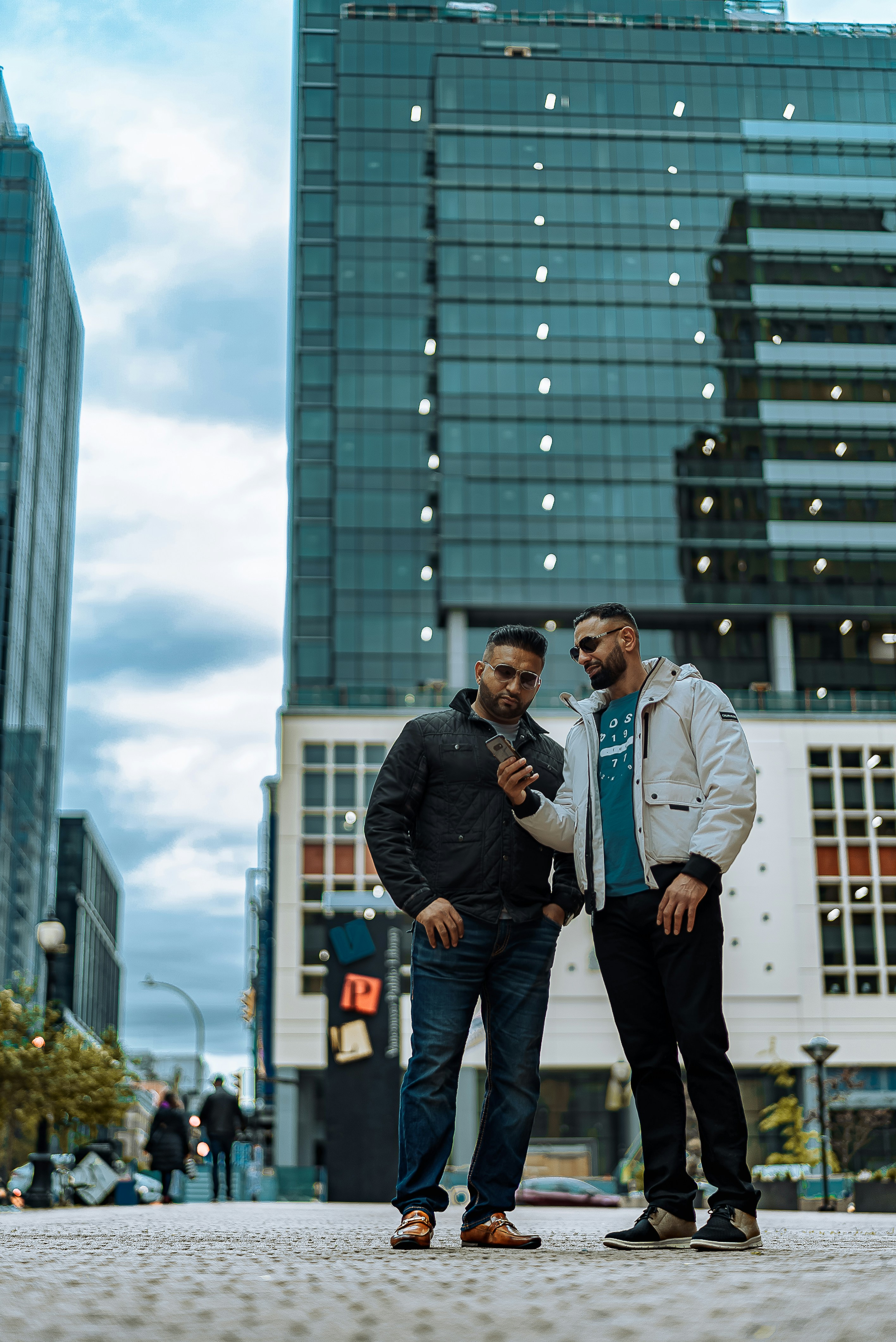 Two men standing next to each other in front of a tall building photo ...