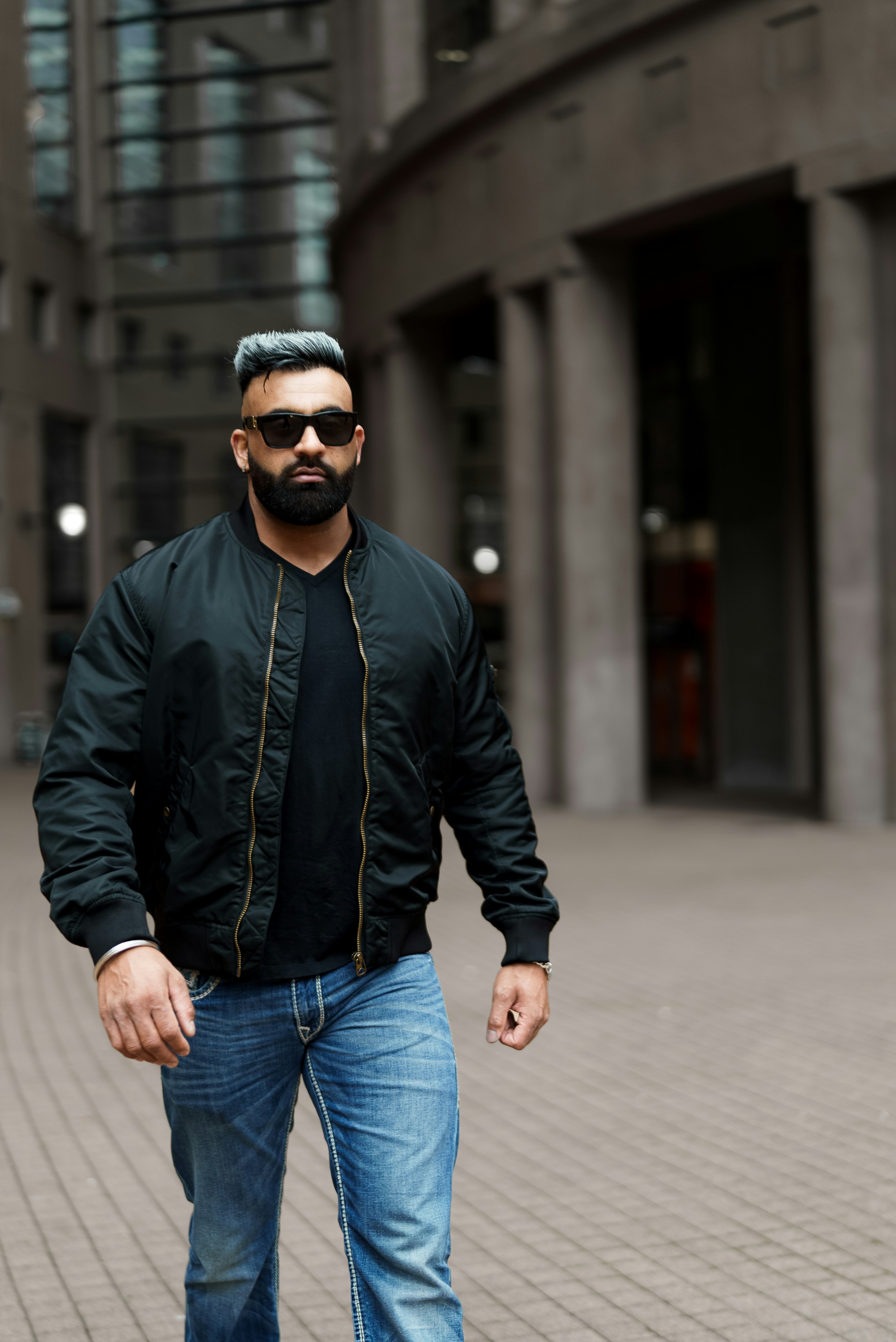 a man in a black shirt and jeans walking down a street