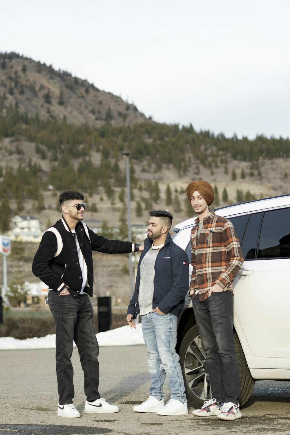 a group of men standing next to a white car