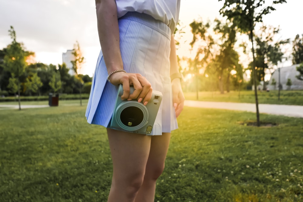 a woman in a white dress holding a camera