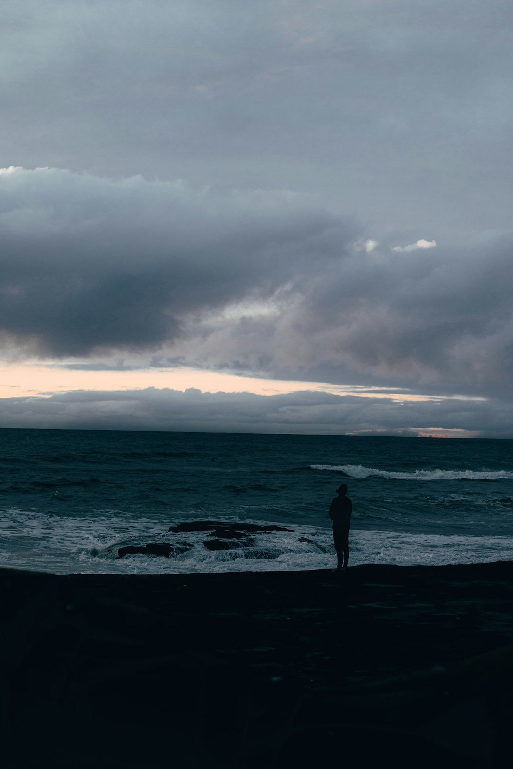 a person standing on a beach next to the ocean