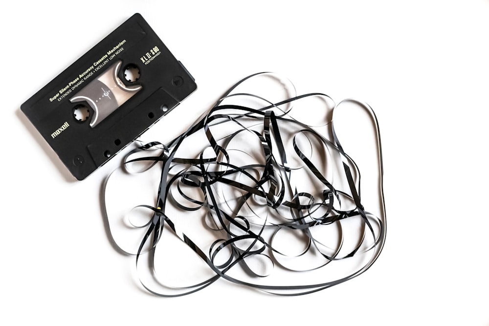 a pile of black cords next to a cassette