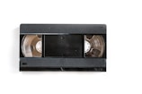 A black VHS tape lies on a white background. The central part features a rectangle with rounded corners, flanked by two open reels showing the tape spools inside.