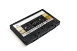 A vintage cassette tape with a black plastic casing and a transparent window, labeled with 'A' on one side and branding information including 'TDK' and 'SA'. The tape has visible spools and labeling indicating 'High Position Type II' and other technical specifications.