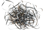 A chaotic tangle of black and shiny film tape sprawled across a white background, forming intricate loops and twists.