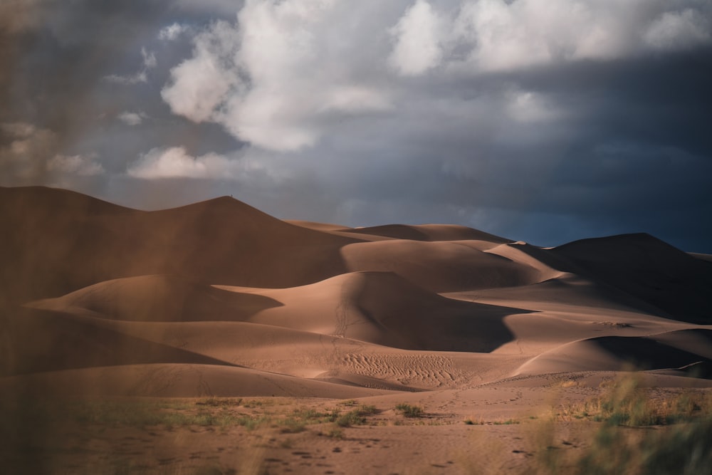a view of a desert with clouds in the sky