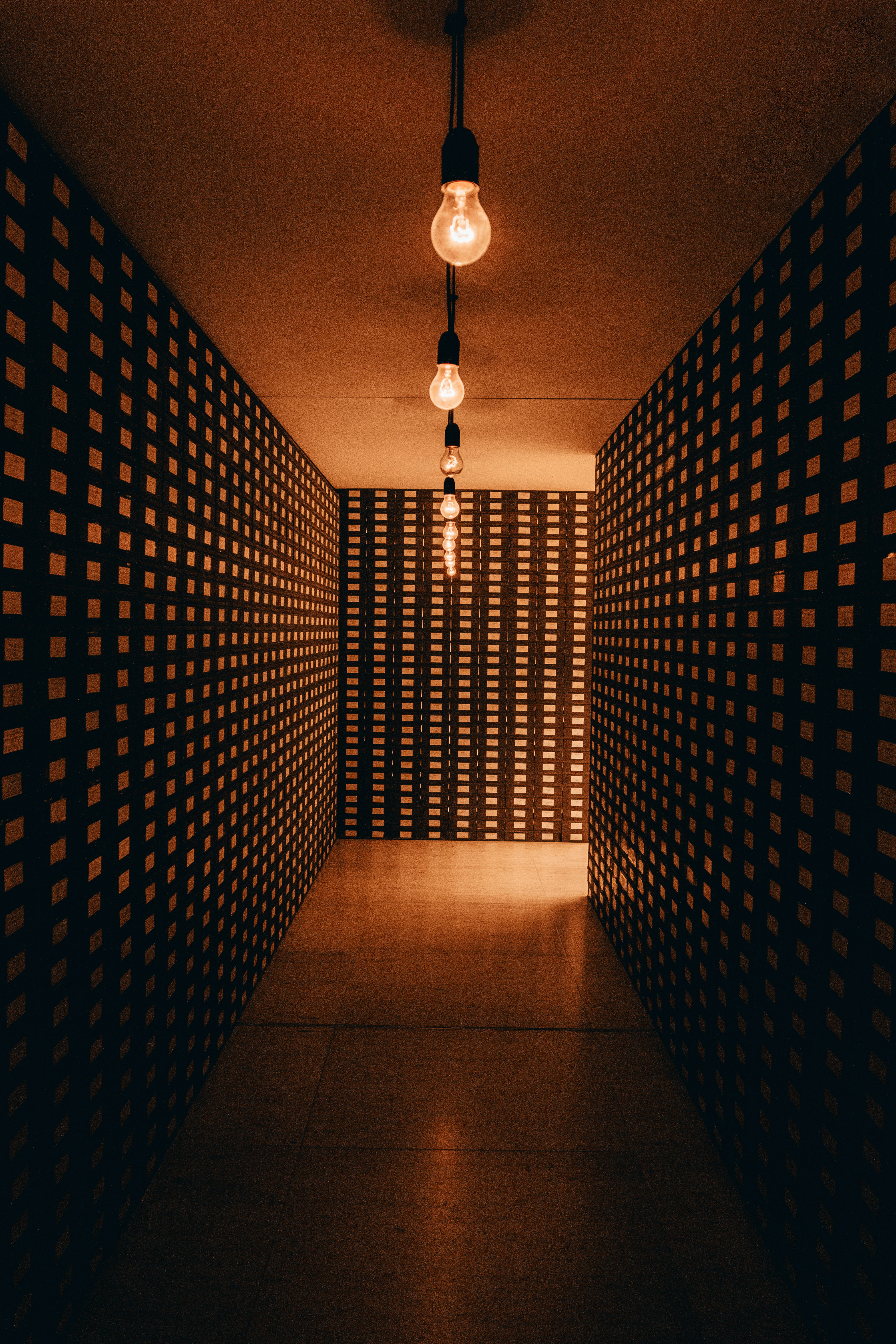 A dimly lit hallway with checkered walls and a light bulb photo – Free ...
