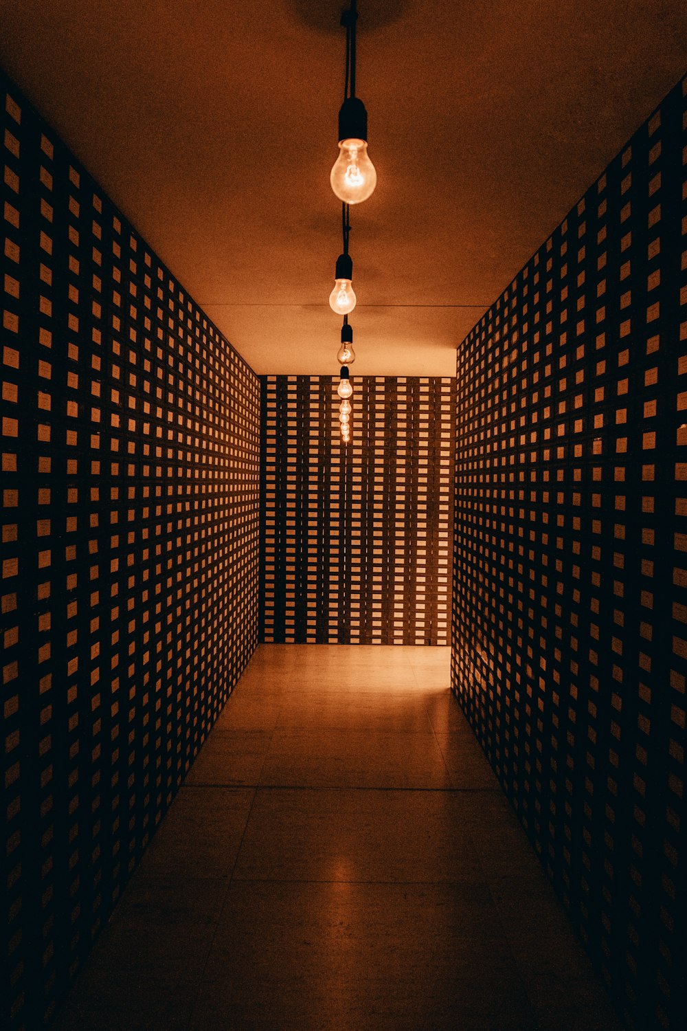 a dimly lit hallway with checkered walls and a light bulb