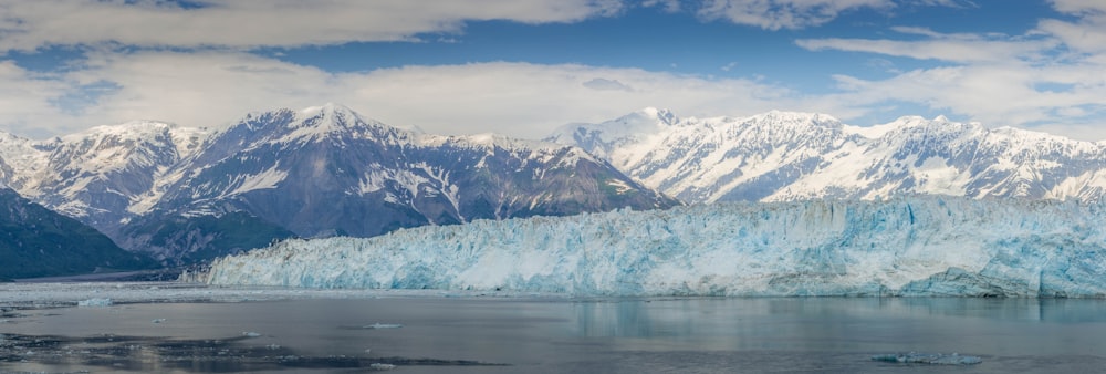 a large glacier with mountains in the background