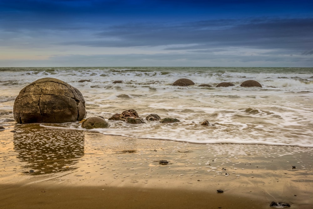 a large rock sitting on top of a sandy beach