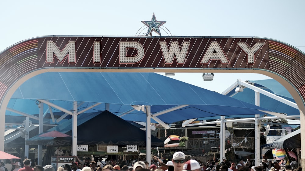 a crowd of people walking under a large sign