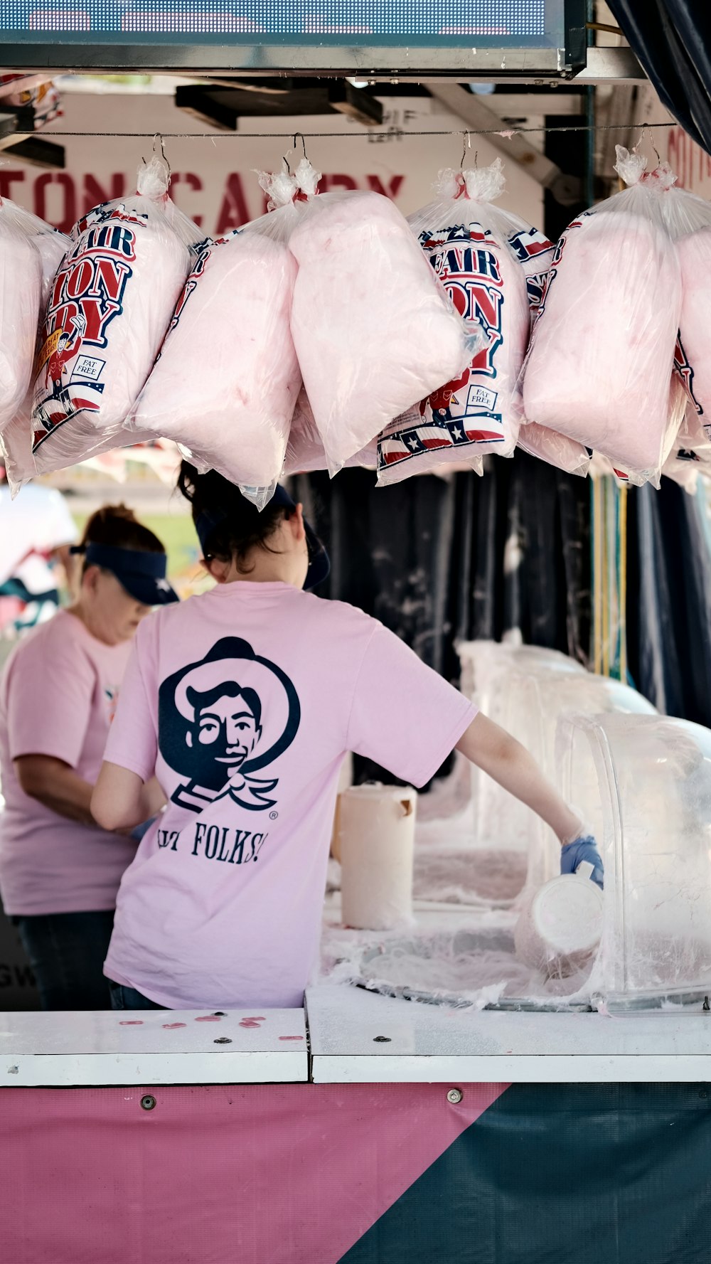 a woman standing behind a counter filled with meat