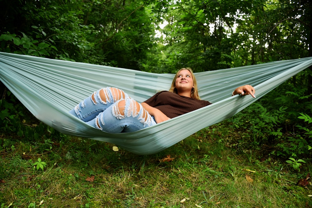a woman laying in a hammock in a forest