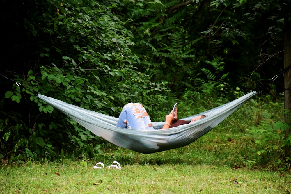 a woman laying in a hammock reading a book