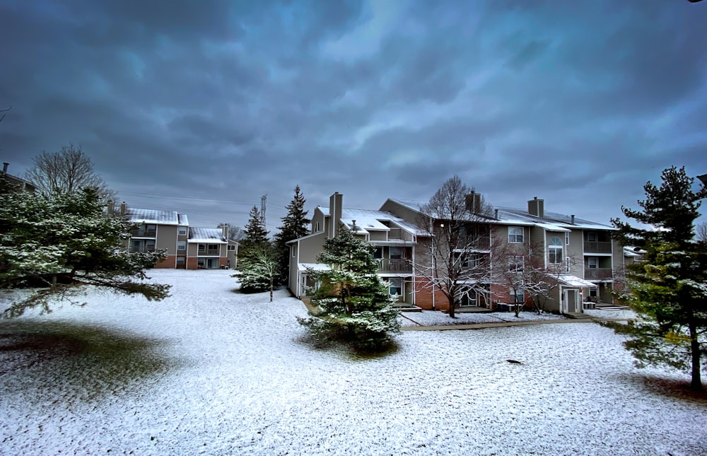 a snow covered yard with trees and buildings in the background