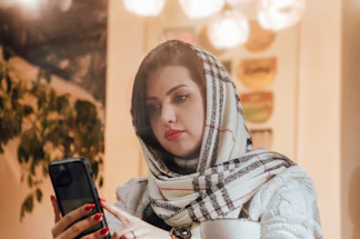 a woman in a scarf looking at a cell phone