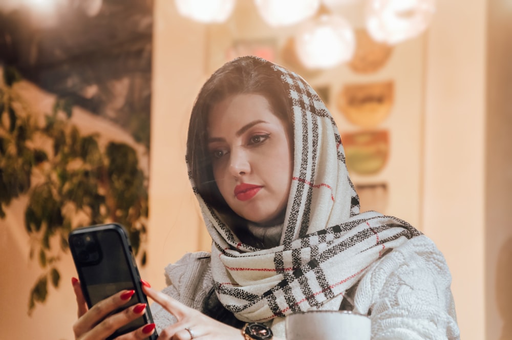 a woman in a scarf looking at a cell phone