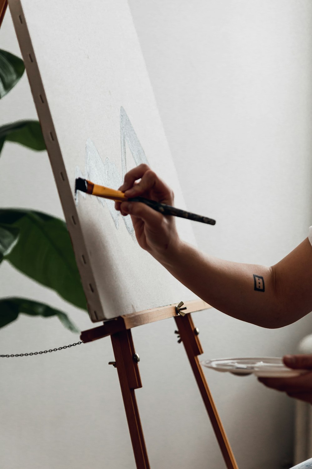 a person holding a paintbrush painting a picture on a easel