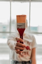 a woman holding a paint brush in her hand