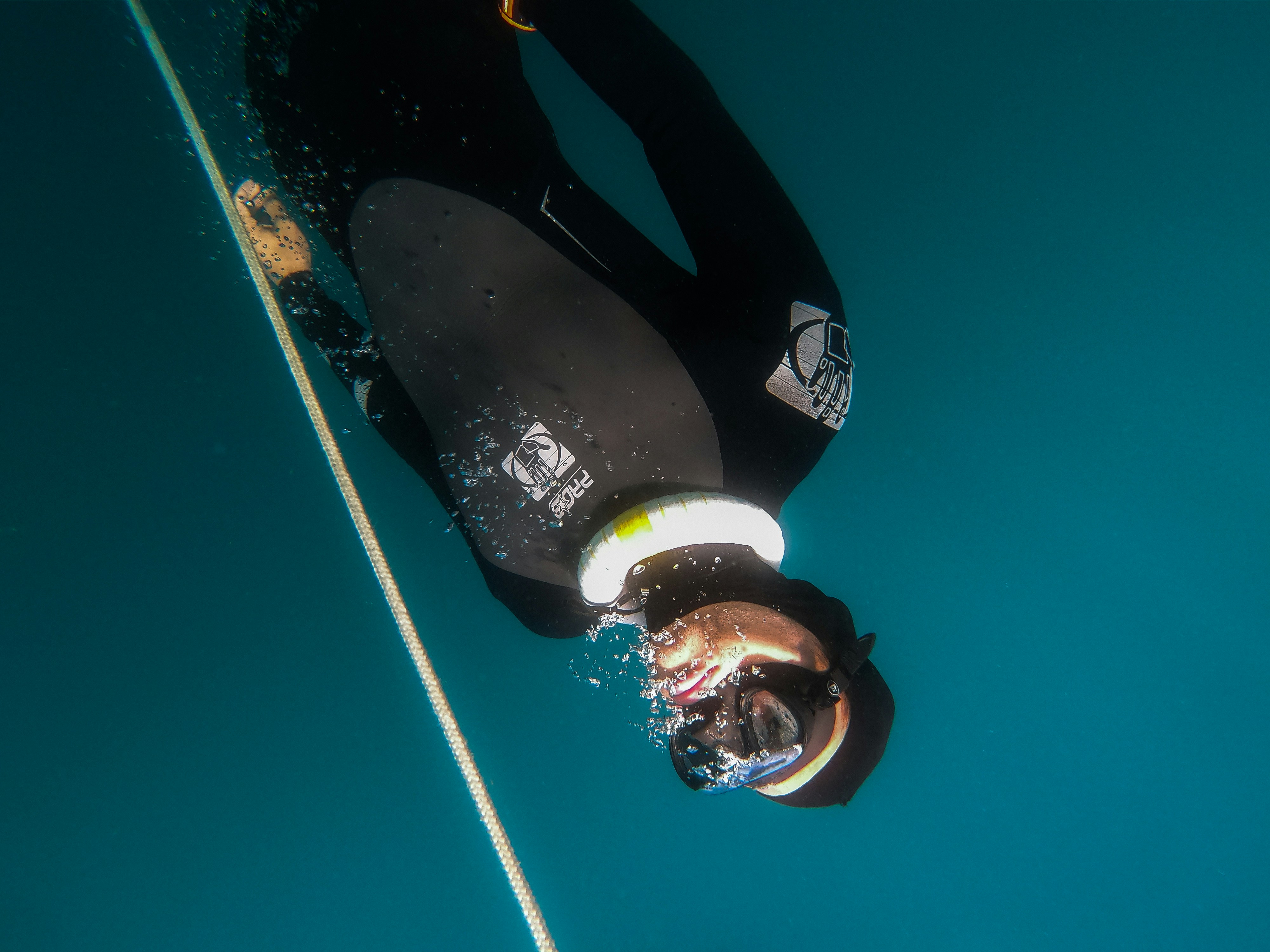 Freediver descending into Blue Hole with sunlight rays