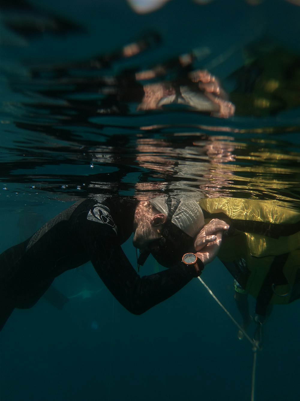 a man in a wet suit holding onto a yellow object in the water