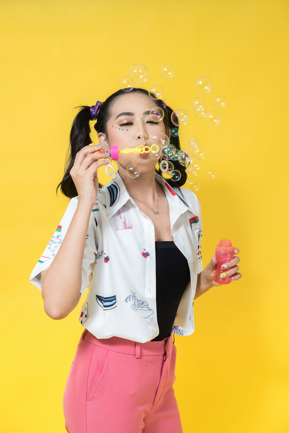 a woman in pink pants blowing bubbles on her face