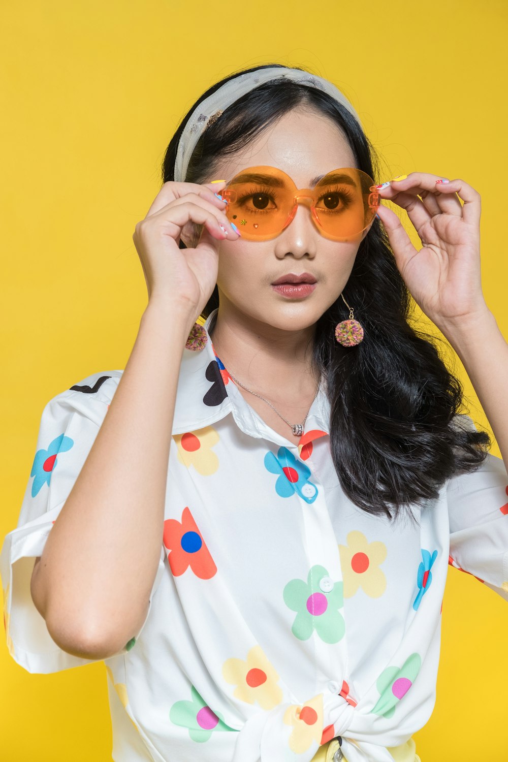 a woman in a polka dot shirt is holding up her glasses