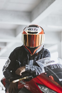 A rider wearing reflective gear standing next to a bright red electric motorbike.