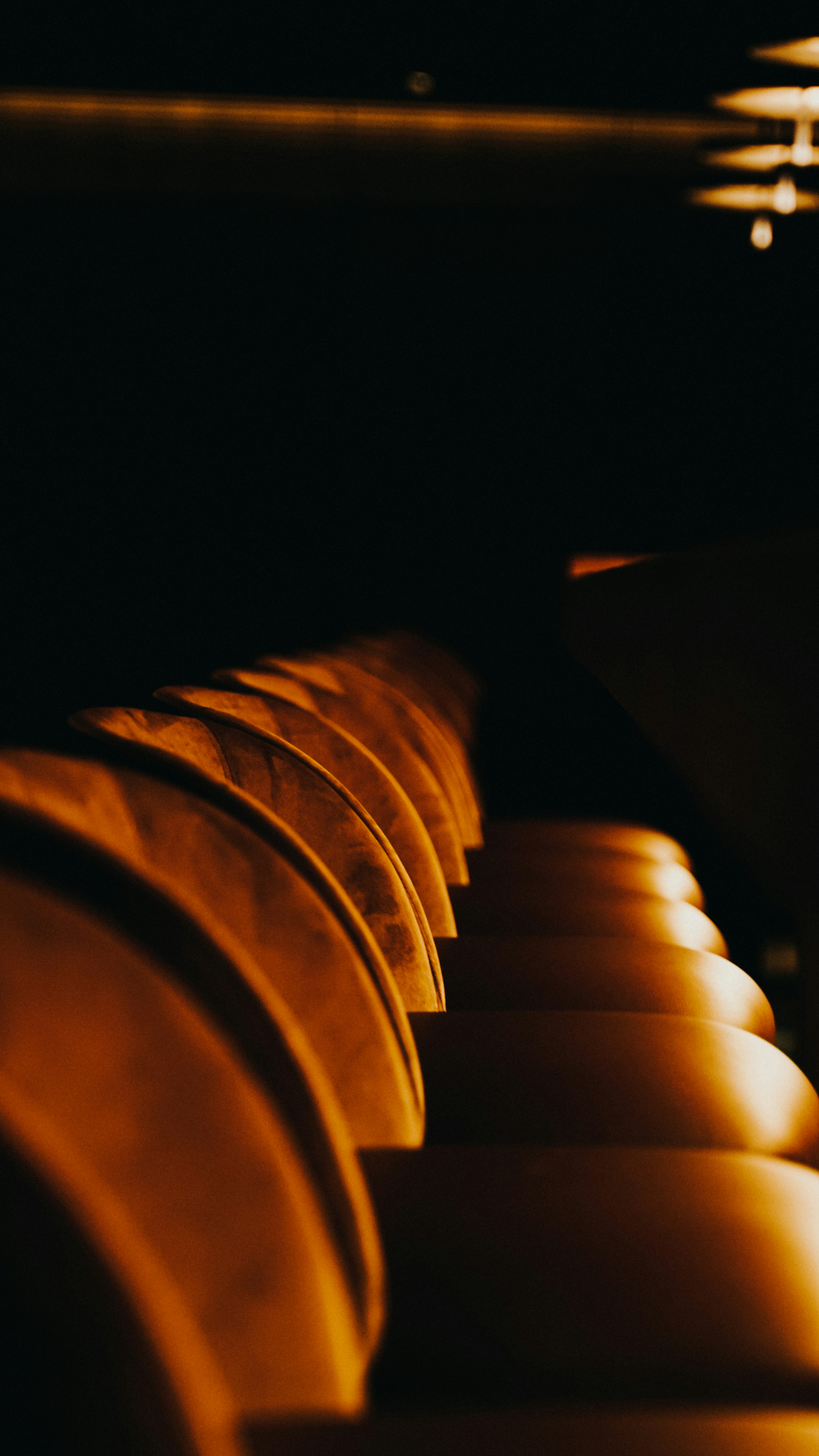 Cinema seats in a dark theater, bright projector light, warm amber glow on empty seats, atmospheric