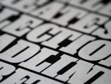 A close-up view of bold, black and white text with a slightly blurred effect, giving the impression of a print or poster design. The letters are large and occupy much of the frame, creating a striking visual impact.