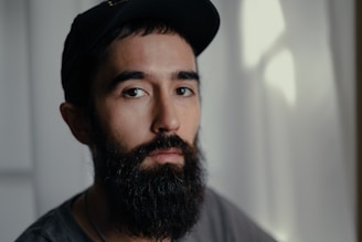 a man with a beard wearing a black hat