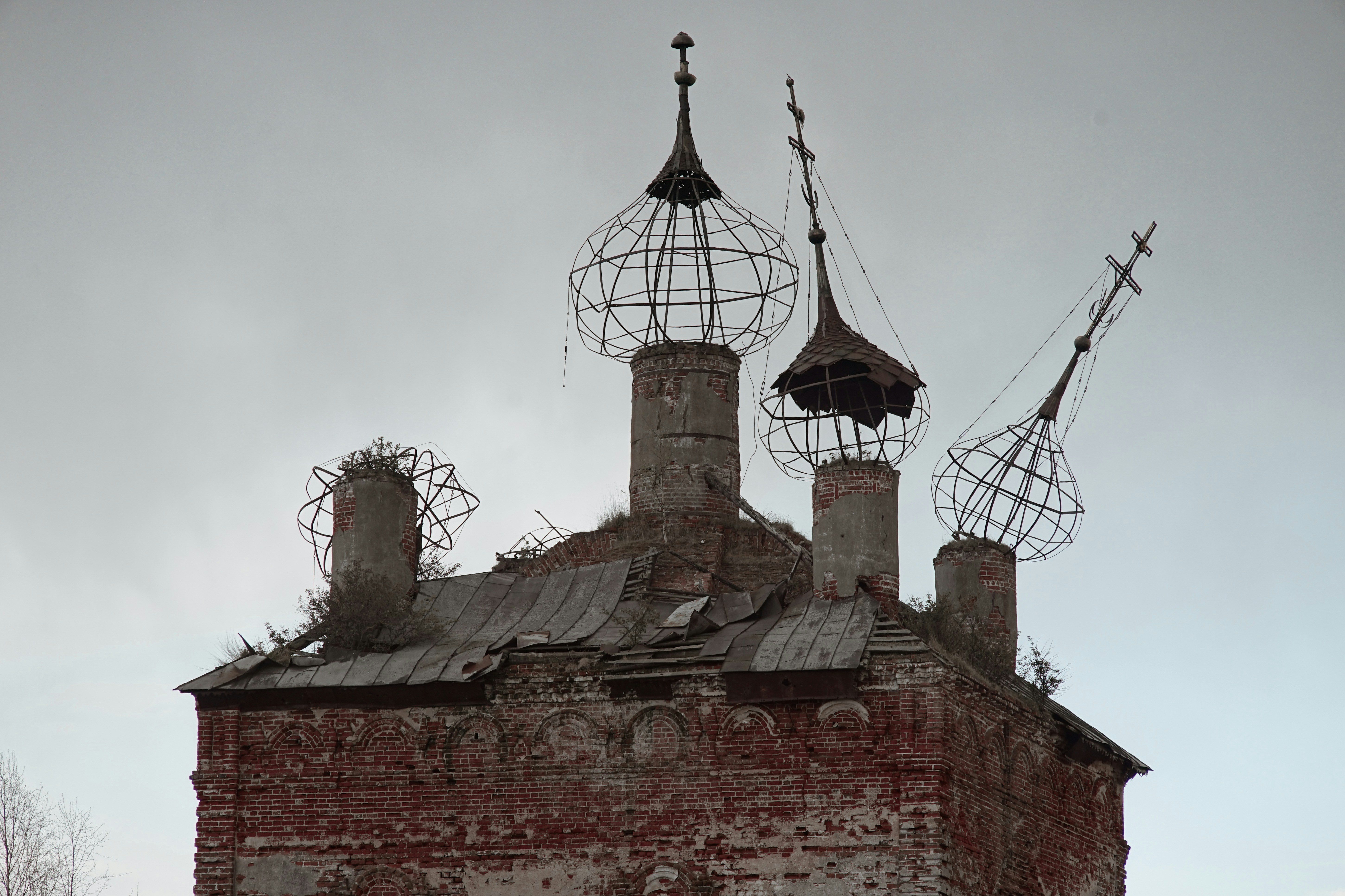 ein altes Backsteingebäude mit zwei Schornsteinen und einer Wetterfahne darüber
