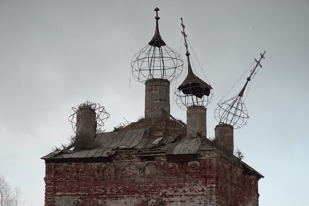 an old brick building with two chimneys and a weather vane on top of it