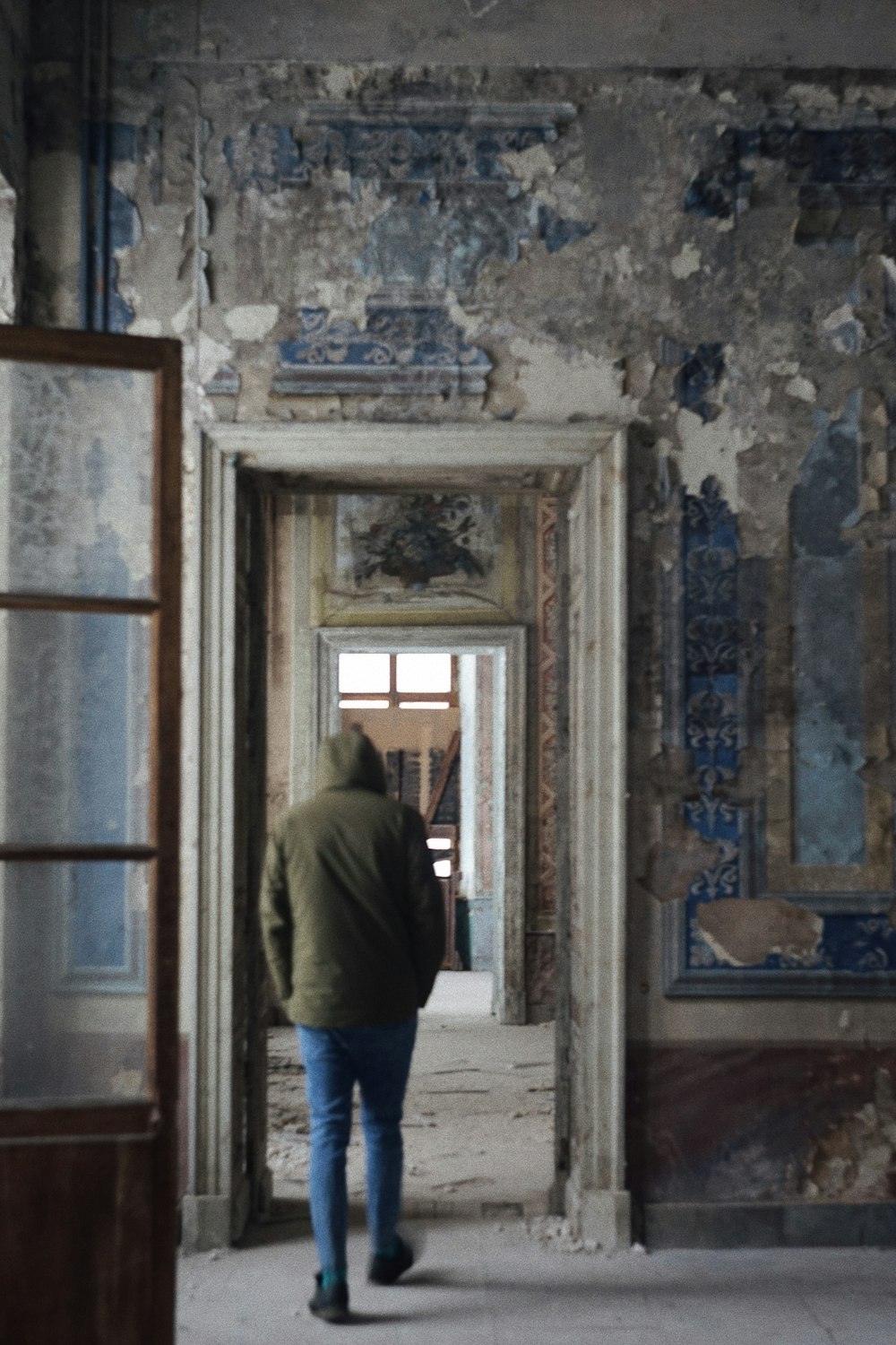 a man in a green jacket walking through a doorway