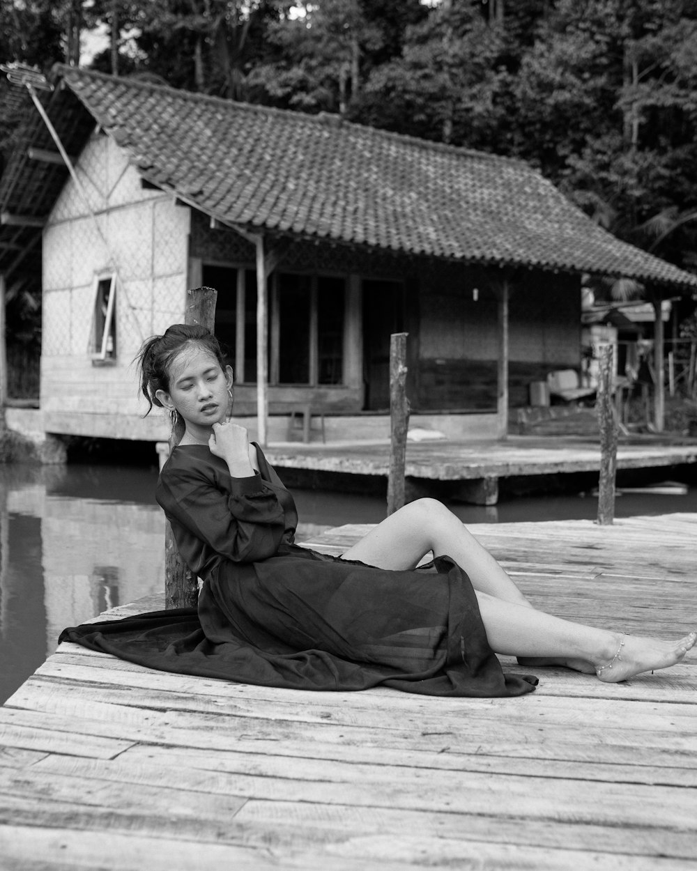 a woman sitting on a dock next to a body of water