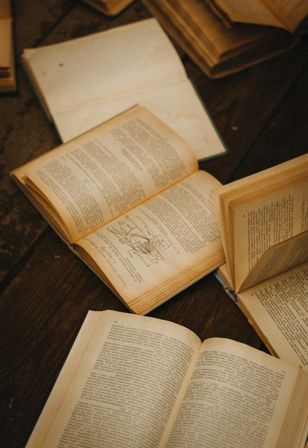 several open books on a table with a pen