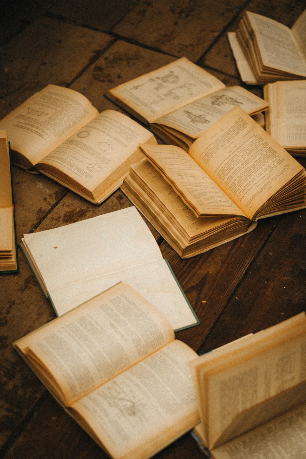 a pile of open books sitting on top of a wooden table