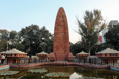 a large monument in a park next to a pond