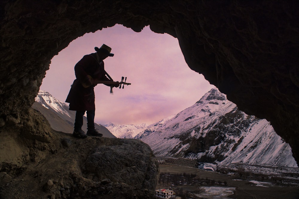 a man standing in a cave holding a guitar