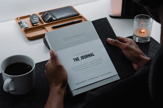 A person journaling beside a warm drink