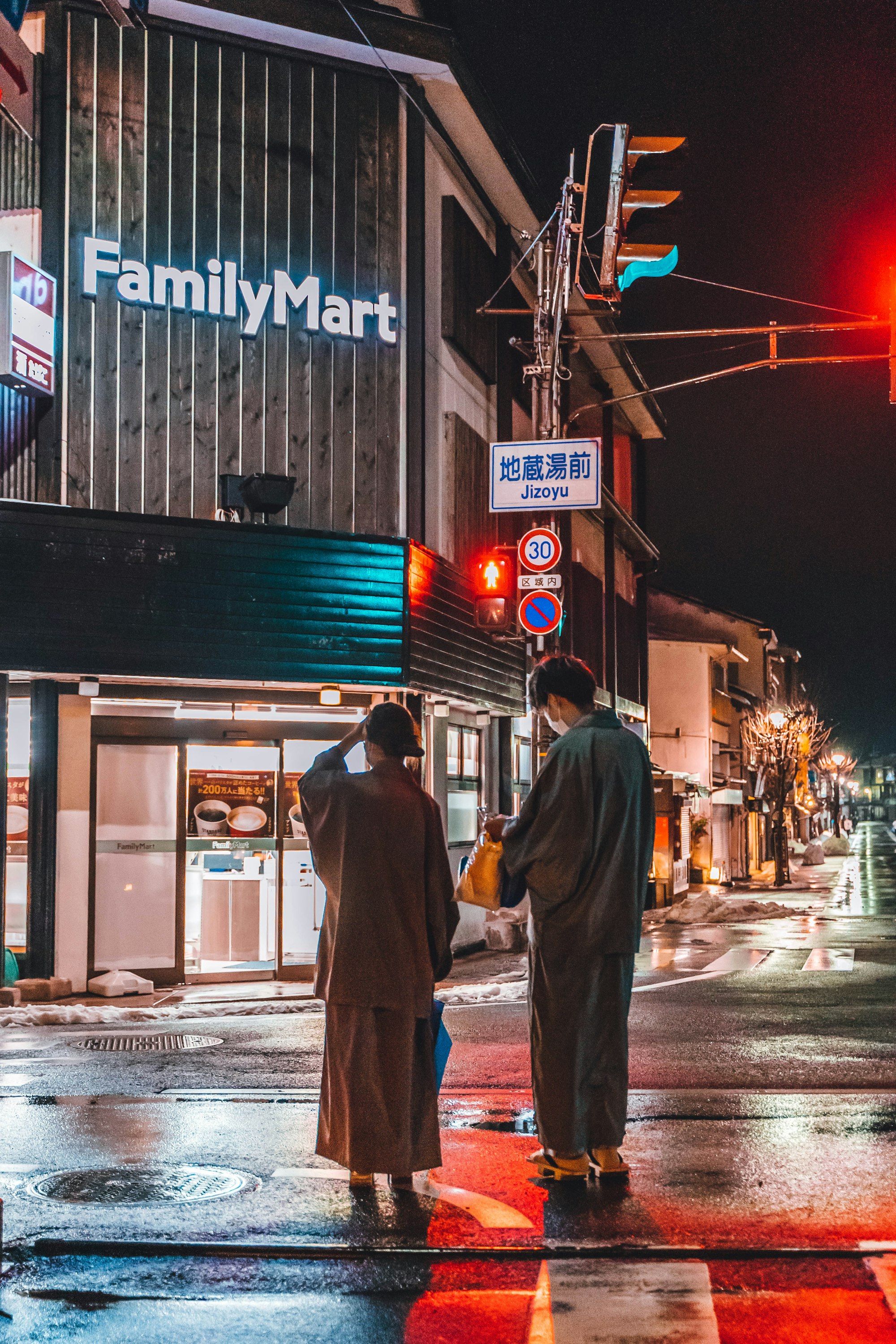 A Japanese couple in the streets of Kinosaki Onsen at night.