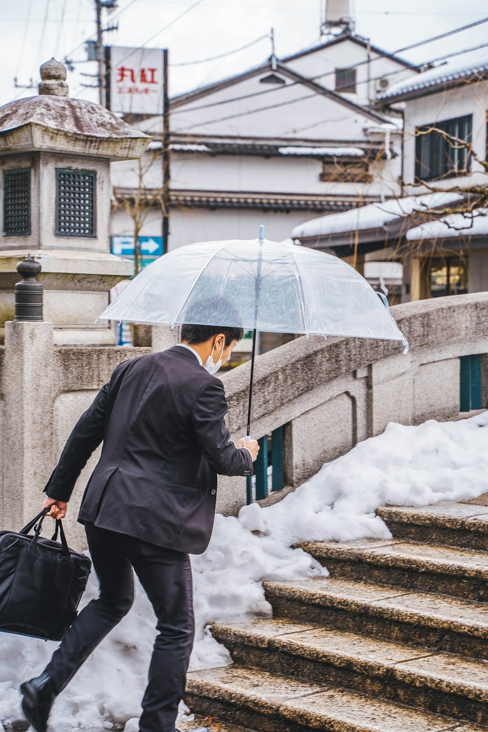 Ein Mann in Anzug und Krawatte, der einen Regenschirm hält