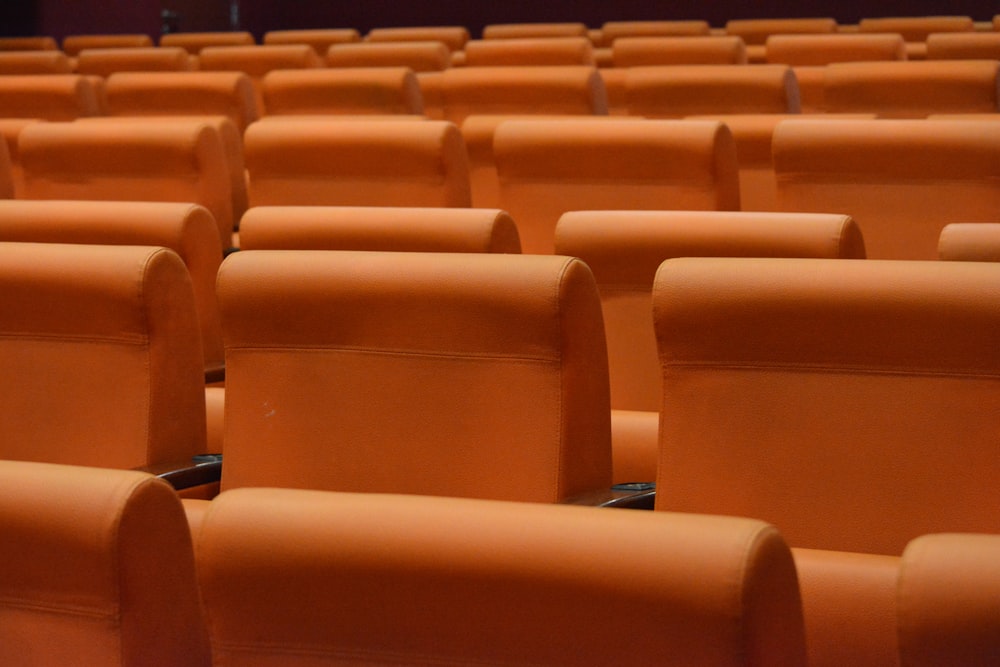 a row of orange seats in a theater