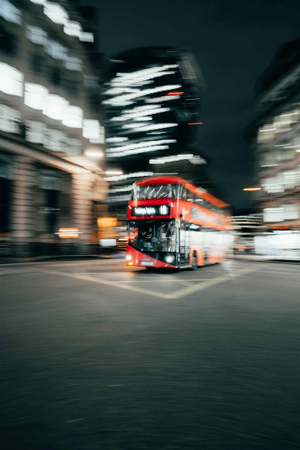 a red double decker bus driving down a street