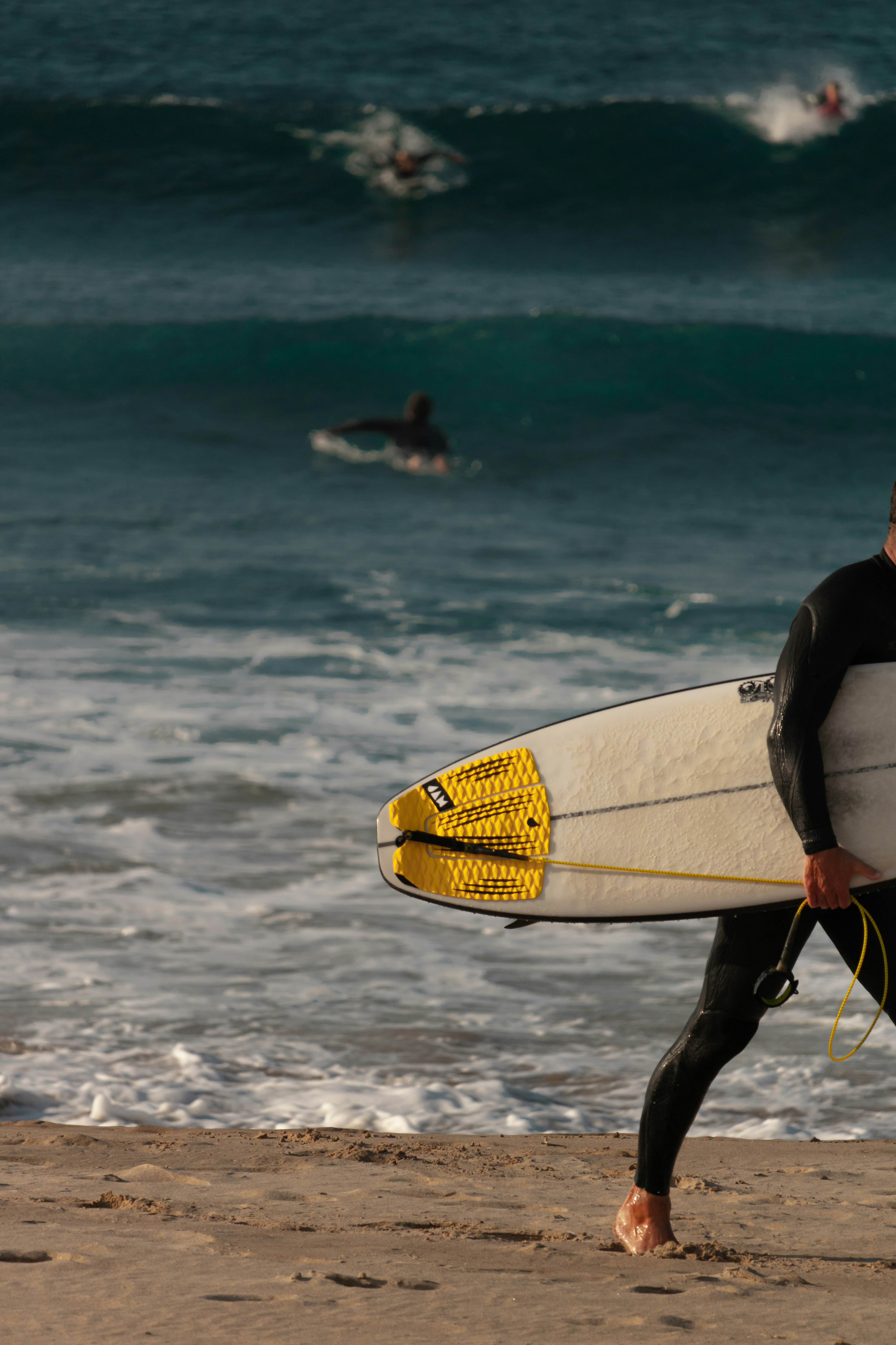 Un uomo in una muta che trasporta una tavola da surf
