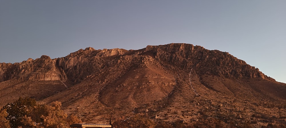 a large mountain with a house in the foreground